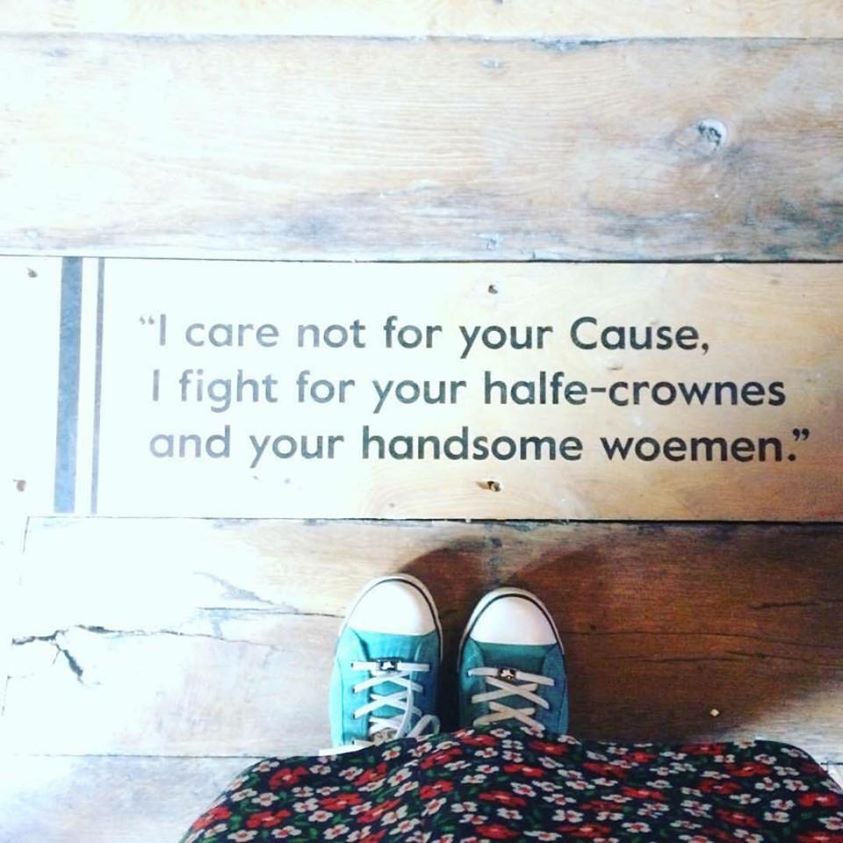 Image shows the words "I care not for your Cause, I fight for your half-crownes and your handsome woemen." The words are stencilled on the floor of the Commandery in Worcester. You can see Tonia's feet standing in front of them, in green trainers and a flowered dress above them. 