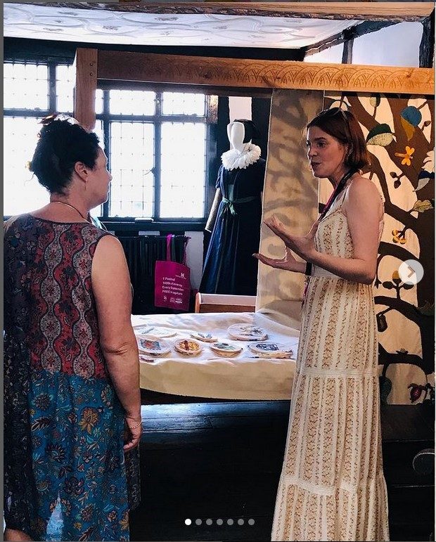 2 women talk together about the Tudor House Bedfellows project in front of a 4 poster bed